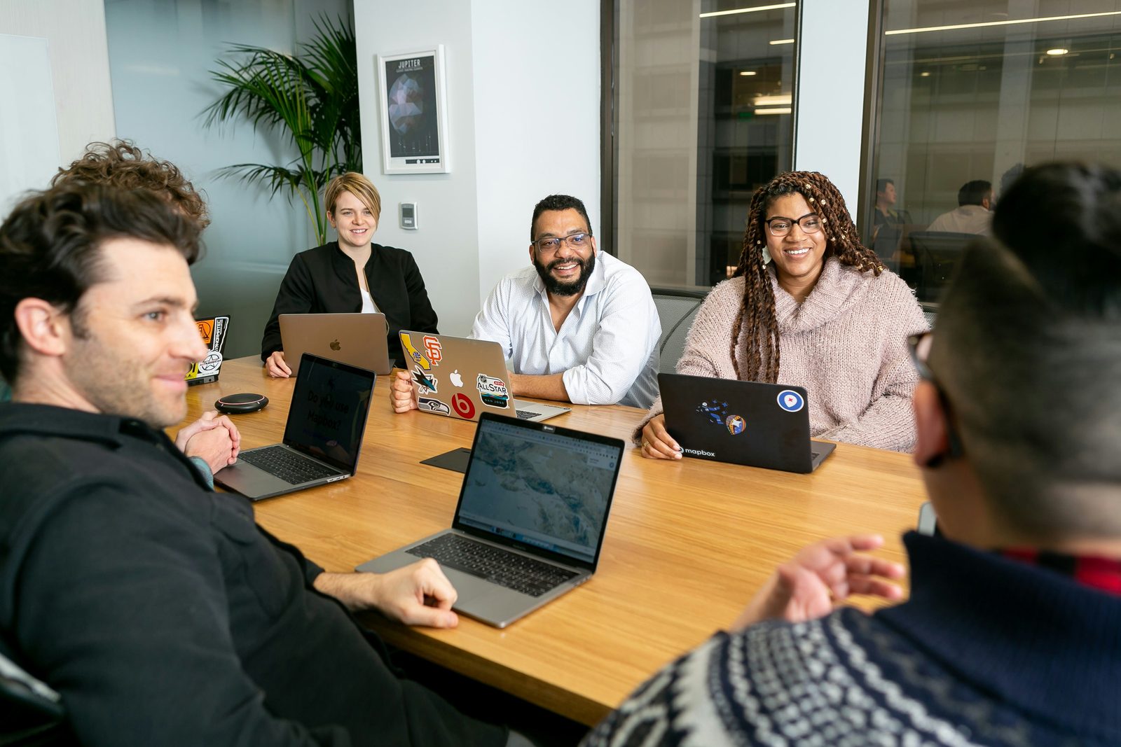 A team gathered around a laptop-covered table, engaged in discussion