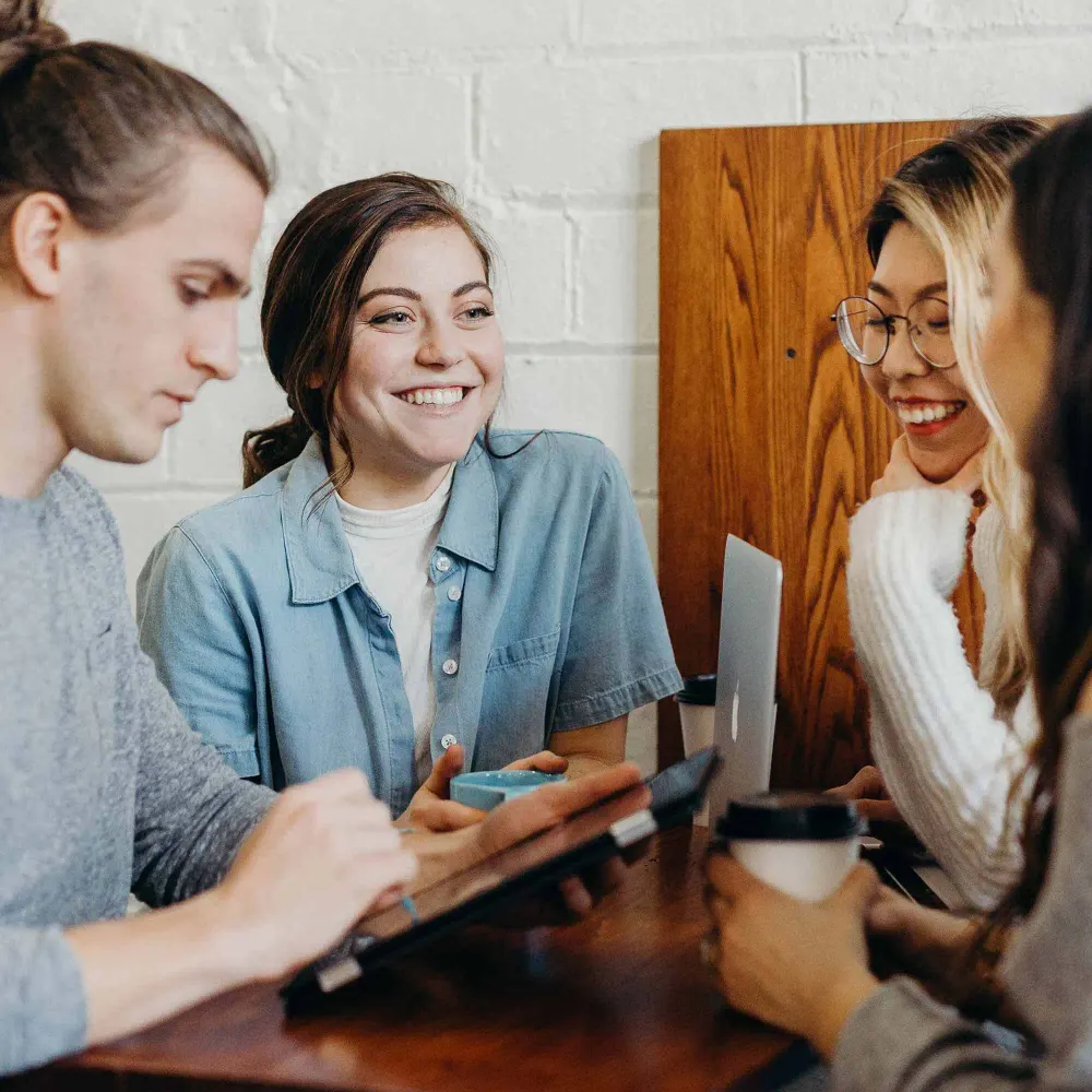 A small group meeting together around a table with laptops and notebooks